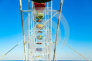 Colorful ferris wheel of the amusement park in the blue sky background