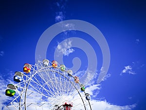 Colorful Ferris wheel with blue sky background at a theme park.