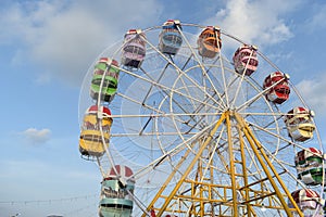 Colorful ferris wheel with blue sky and white clouds in the background