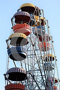 Colorful ferris wheel slowly moving against blue sky in the amusement park