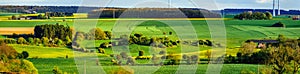 Colorful fields in belgian countryside panoramic view with windmill on horizon