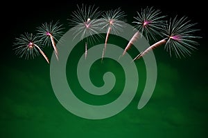 Colorful fireworks display on green background