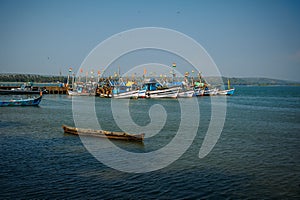 Colorful fishing boats with blue and white hulls and Indian flags on the masts, on the fishing pier in Goa. Wooden boats