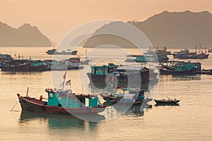 Colorful fishing boats on a sea near to rock islands on sunset. Ha Long Bay, Vietnam