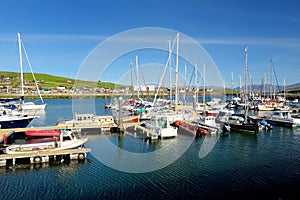 Colorful fishing boats and yachts at the harbor of Dingle town on the West Atlantic coast of Ireland. Small towns and villages on
