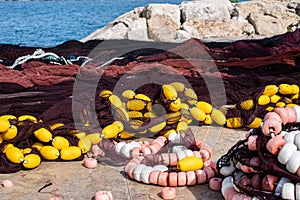 Colorful fishing buoys and nets strewn on a jetty, telling a story of maritime labor and ocean bounty against a coastal