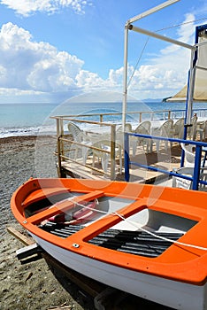 Colorful fishing wooden boat moored on the beach - coral color