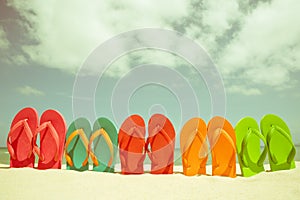 Colorful flip flop on sandy beach, green sea and blue sky