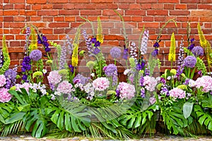 Colorful flowers against red brick wall, different blossoms, wedding decoration, postcard