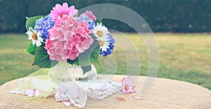 Colorful flowers bouquet in glass vase on green.