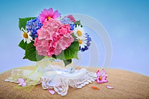 Colorful flowers bouquet in glass vase isolated on blue.