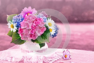 Colorful flowers bouquet in glass vase isolated on pink.