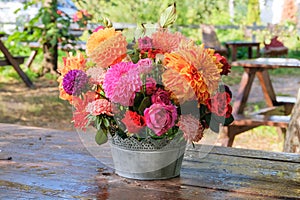 Colorful flowers: roses, asters, dahilia in the apple garden on a wooden table. Bright rural design. Sunny day