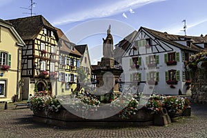 Colorful and flowery facade with village fountain in Eguisheim, Alsace, France