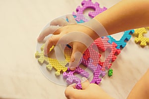 Colorful foam puzzle letters and numbers in kid`s hands on a light table