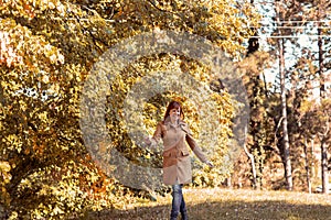 Colorful foliage in the park. Falling leaves natural background. Happy red hair woman in nature