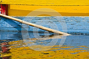 Detail of yellow, blue and red Trajinera boat and its reflection, in Xochimilco, Mexico