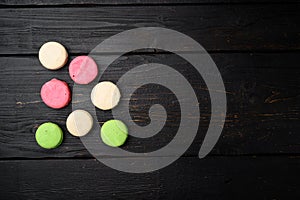 Colorful french macarons, on black wooden table background, top view flat lay, with copy space for text