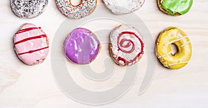 Colorful fresh donuts on white wooden background