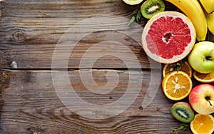 Colorful fresh summer fruits on brown wooden background, healthy food, top view