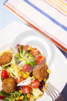 Colorful fresh vegetable salad with meatballs and corn seeds