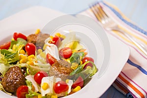 Colorful fresh vegetable salad with meatballs and corn seeds