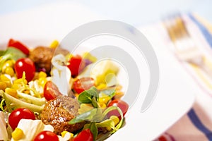 Colorful fresh vegetable salad with meatballs and corn seeds