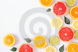 Colorful fruit corner border of citrus slices and leaves, top view over a white background