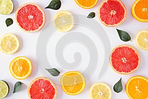 Colorful fruit frame of citrus slices and leaves, top view over a white background