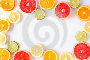 Colorful fruit frame of citrus slices, top view over a white background