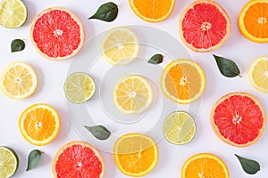 Colorful fruit pattern of citrus slices and leaves, top view over a white background