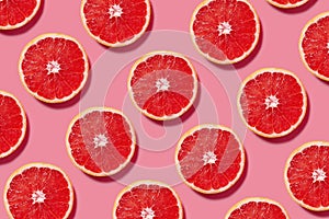 Colorful fruit pattern of fresh grapefruit slices on pink background photo