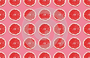 Colorful fruit pattern of grapefruit slices on pink background.