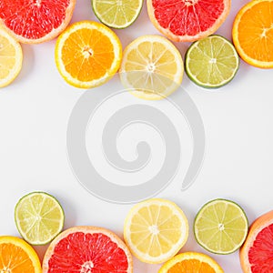 Colorful fruit square double border of citrus slices, top view over a white background
