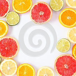 Colorful fruit square frame of citrus slices, top view over a white background
