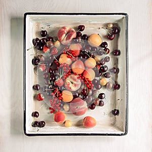 Colorful fruits and berries fresh from the market, decorated in a vintage baking tray, free space for your text