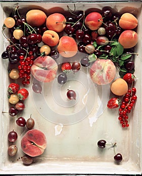 Colorful fruits and berries fresh from the market, decorated in a vintage baking tray, free space for your text