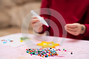 Colorful fusible beads or perler beads, on the children`s table. Toy that develops the imagination of child. Soft blurred