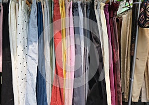 Colorful garments hang on rack at market stall