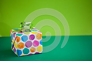 Colorful gift box on lime color background. Holiday greeting card