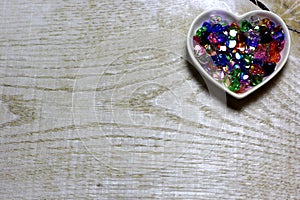 Colorful glass beads hearts on wooden background.