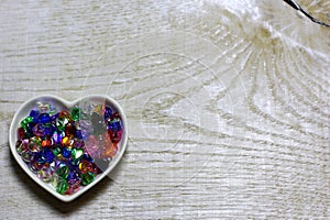 Colorful glass beads hearts on wooden background.