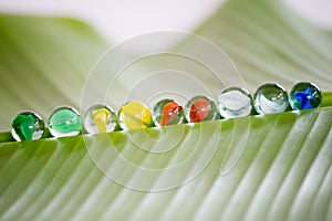 Colorful glass marbles on banana leaf