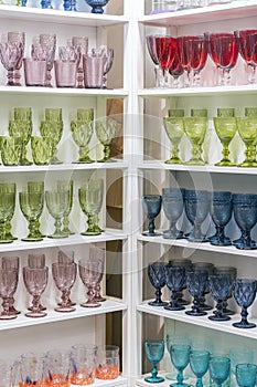 Colorful glasses and vases on the shelf in the souvenir shop. wine glasses stand on the shelves in a large supermarket. vertical