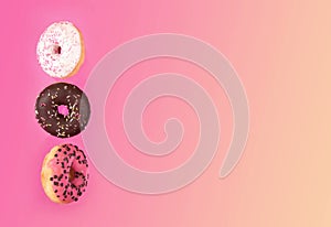 Colorful glazed donuts in motion on pink background.