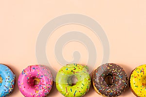 Colorful glazed donuts on pastel background with copy space.