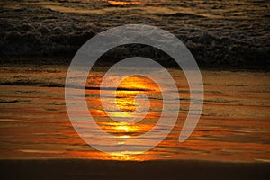 Colorful golden sunset on the beach. The sunset rays are reflected in the sea and sand.