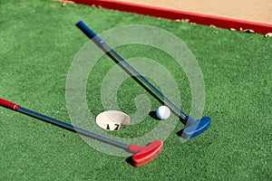 colorful golf putters with golf balls on synthetic grass