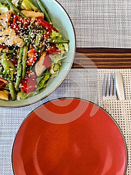 Colorful Gourmet Salad on a Modern Dining Table. Vibrant bowl of salad topped with sesame seeds served on an elegantly set table