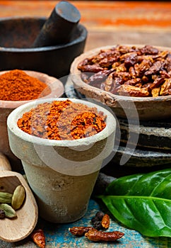 Colorful ground spicy chili peppers , pimento and curcuma is clay pots close up